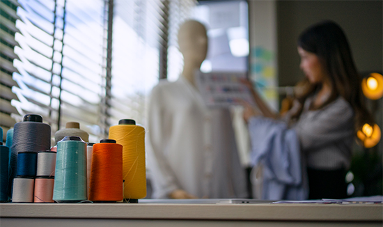 Colorful sewing threads with designer, showcasing HLK Group’s fashion sourcing