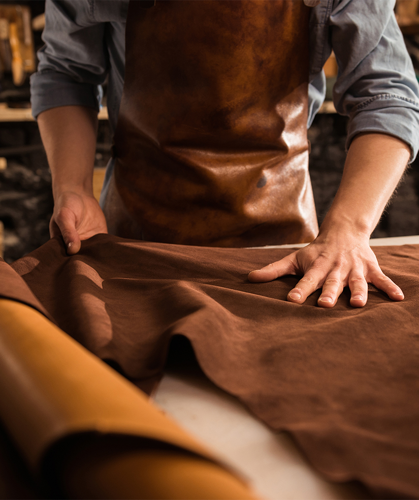 Craftsman inspecting premium leather material, representing HLK Industries’ commitment to quality, sustainability, and ethical fashion sourcing.